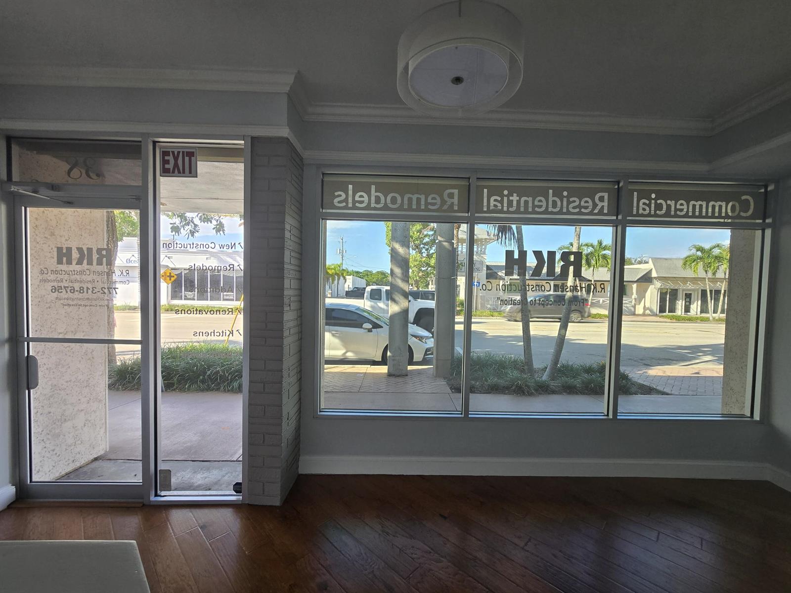 An interior view of a commercial office space with large windows, wood flooring, and brick accents — 38 SE Ocean Boulevard # 38, Stuart FL 34994, STUART, FL