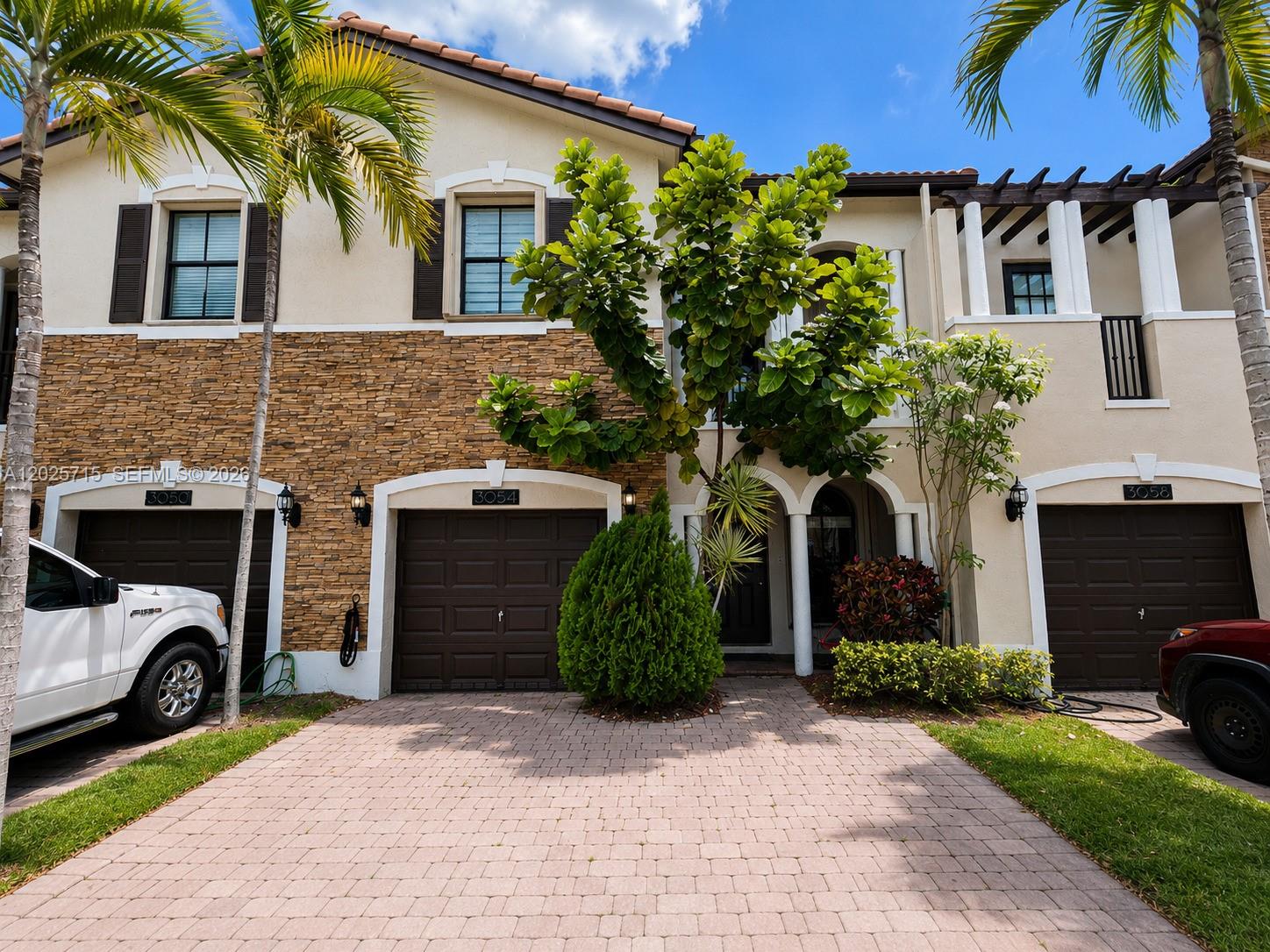 A multi-unit residential building features stone veneer, brown garage doors, and a paved driveway — 3054 NW 103rd Path, Doral FL 33172, DORAL, FL