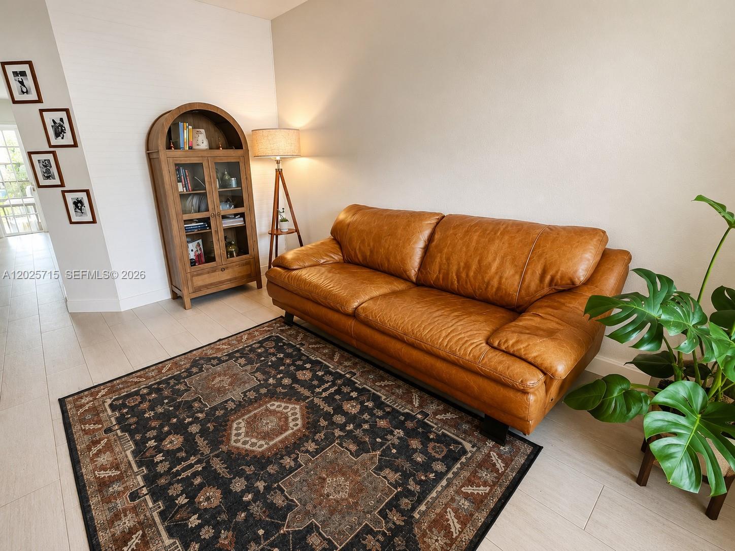 A living room features a brown leather sofa, a patterned rug, and a wooden cabinet — 3054 NW 103rd Path, Doral FL 33172, DORAL, FL