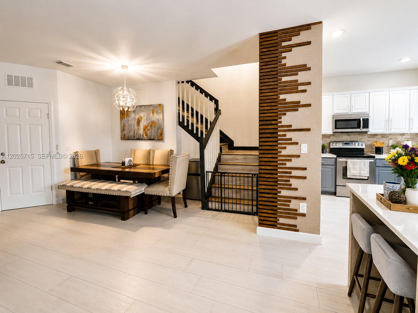 A dining area with a wooden table and bench sits beside a staircase with slats — 3054 NW 103rd Path, Doral FL 33172, DORAL, FL