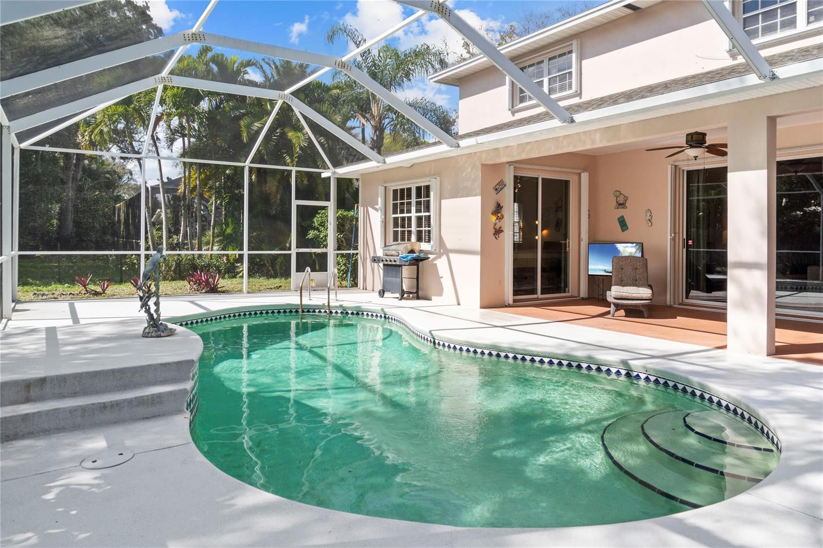 A screened-in swimming pool sits on a concrete patio next to a two-story house — 2148 Buena Vista Boulevard, Vero Beach FL 32960, VERO BEACH, FL