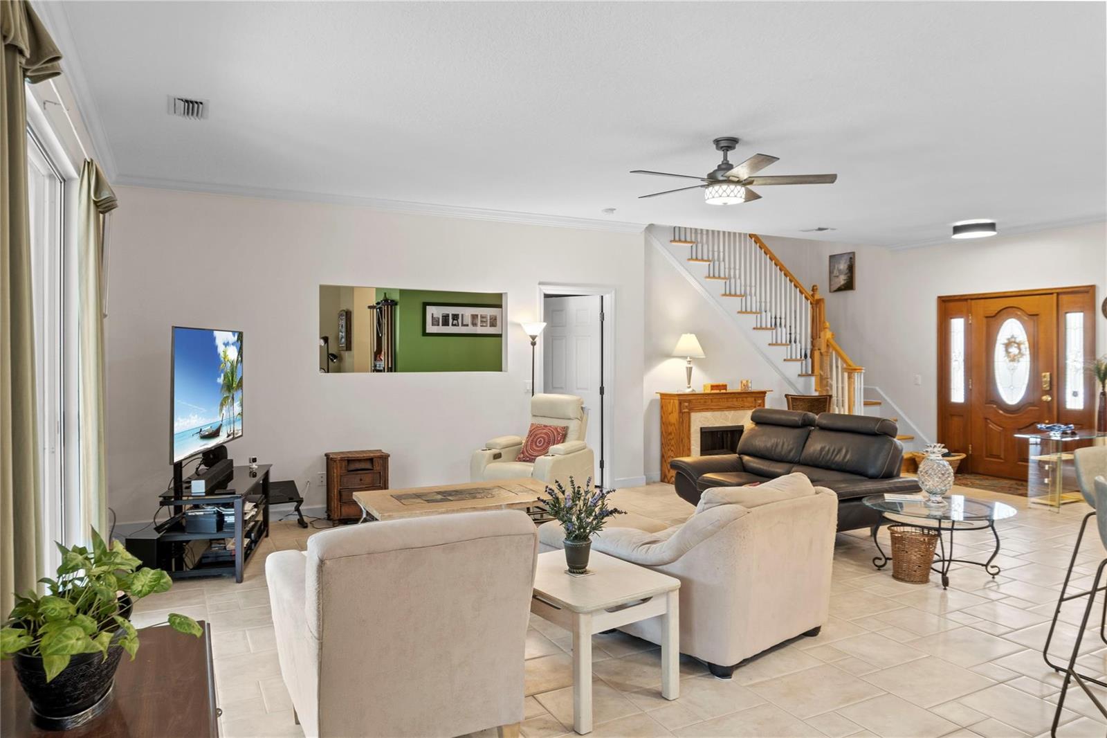 A living room features tile flooring, a staircase, a fireplace, and a television console — 2148 Buena Vista Boulevard, Vero Beach FL 32960, VERO BEACH, FL