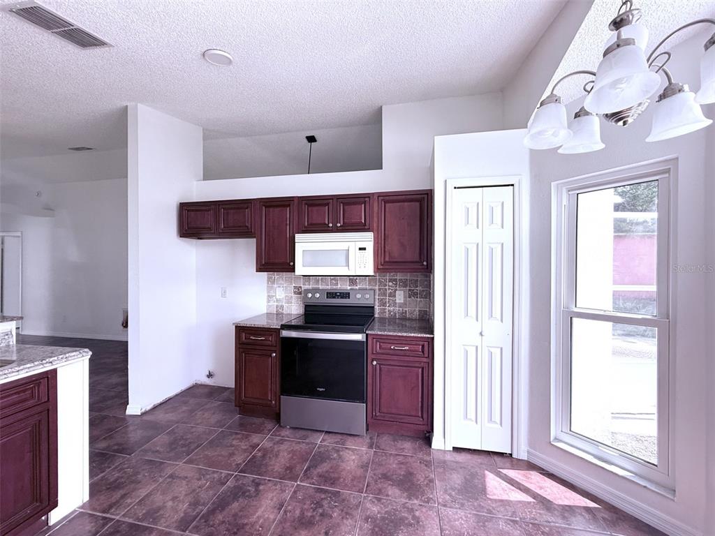 A kitchen features dark wood cabinets, stainless steel appliances, tile flooring, and a white pantry — 7219 EDGEWATER SHORES COURT, ORLANDO, FL