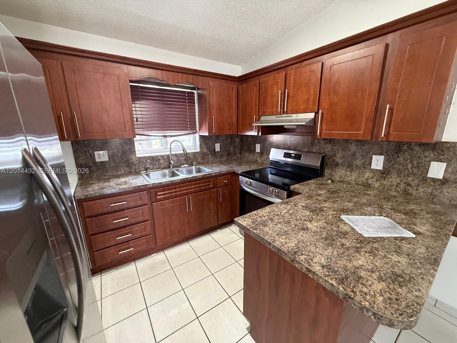 A kitchen features wood cabinets, brown laminate countertops, stainless steel appliances, and white tile flooring — 2212 W 74th St # 28, Hialeah FL 33016, HIALEAH, FL