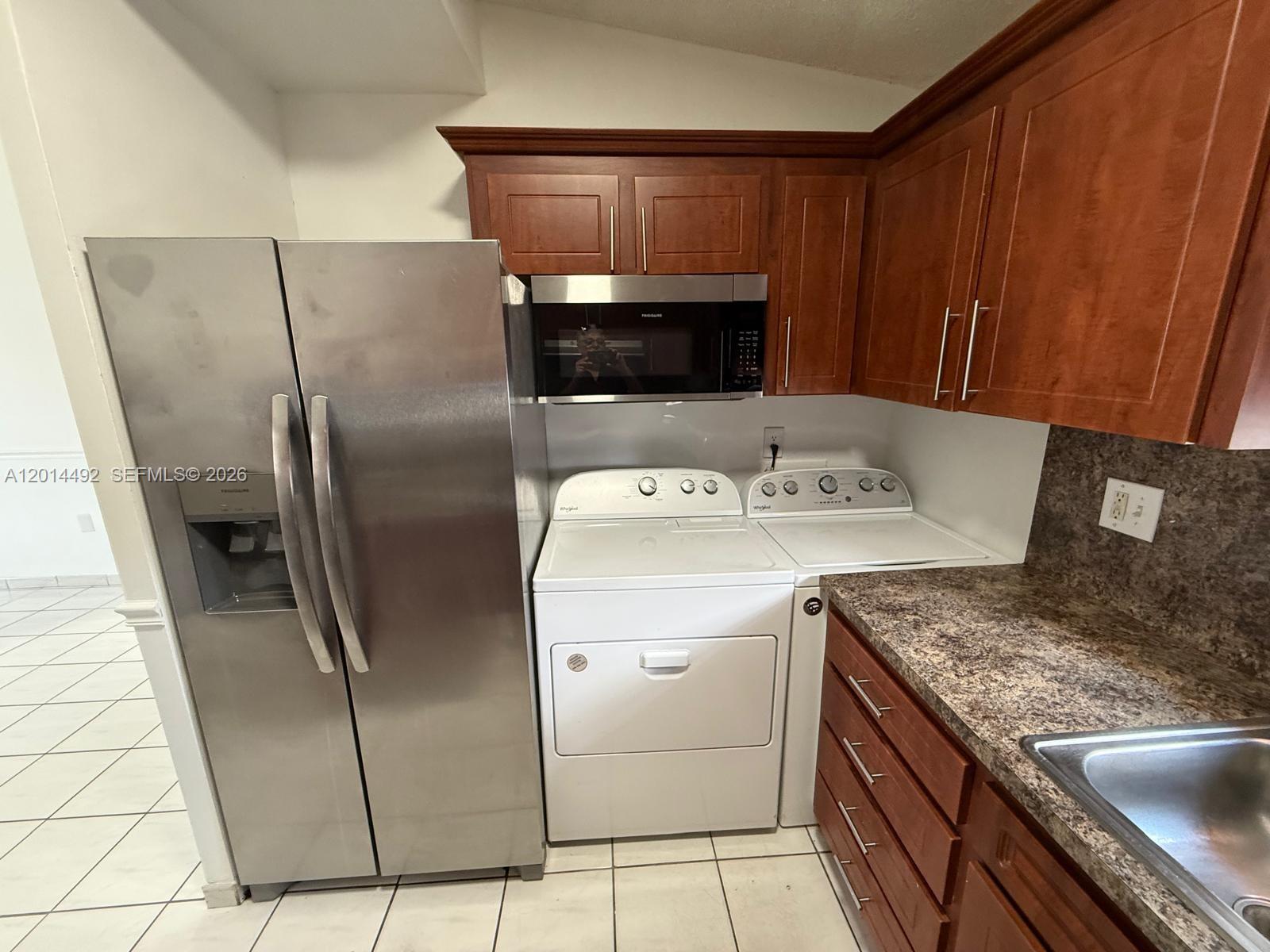 A kitchen features stainless steel appliances, wood cabinetry, and a side-by-side laundry unit — 2212 W 74th St # 28, Hialeah FL 33016, HIALEAH, FL