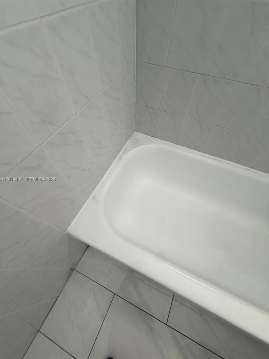 A white bathtub is installed against tiled walls and a tiled floor — 2212 W 74th St # 28, Hialeah FL 33016, HIALEAH, FL