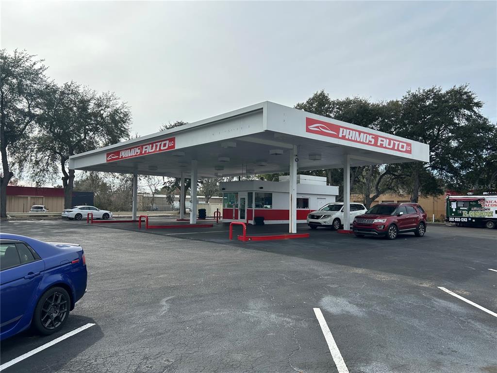 A former gas station converted into a car dealership with a large white canopy — 1516 N MAIN STREET, GAINESVILLE, FL