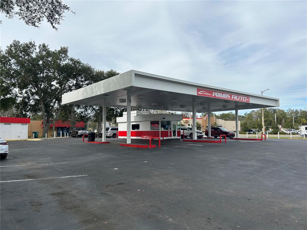 A large, white, flat-roofed canopy covers a small office building at a car dealership — 1516 N MAIN STREET, GAINESVILLE, FL