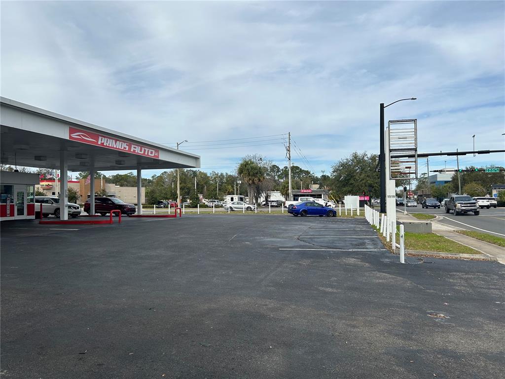 The exterior of a car dealership features a covered service area and a paved parking lot — 1516 N MAIN STREET, GAINESVILLE, FL