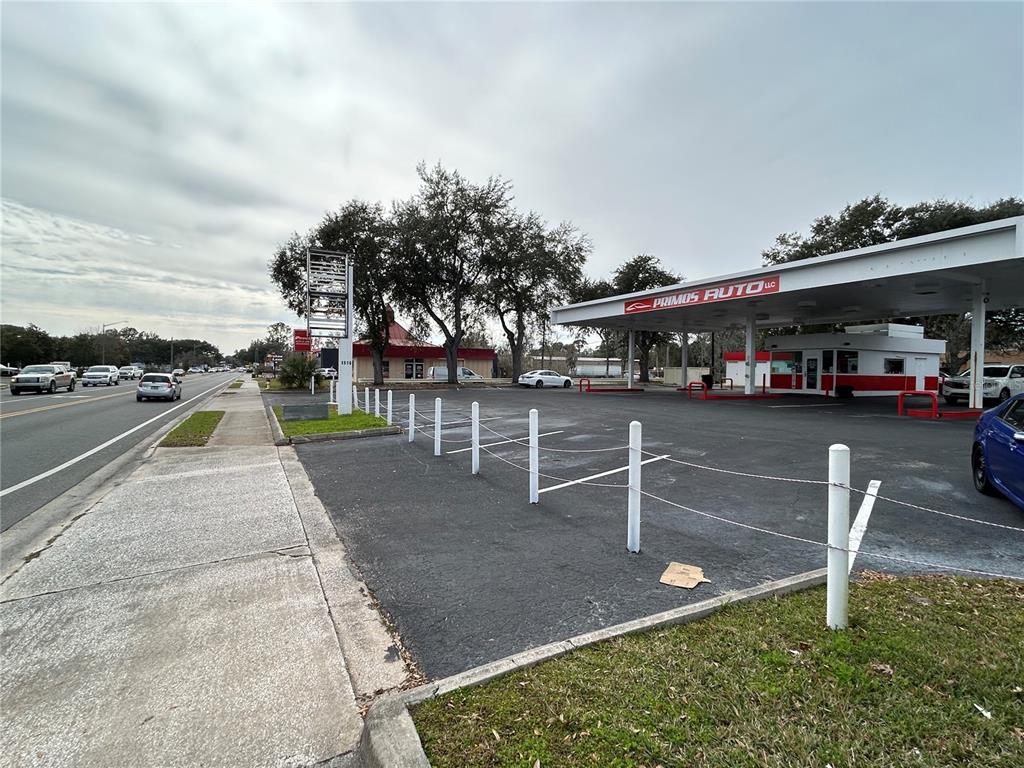 An exterior view of a car dealership lot with a covered service area and parking — 1516 N MAIN STREET, GAINESVILLE, FL