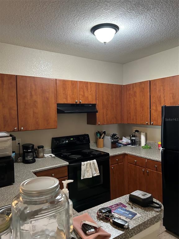 A kitchen features wood cabinets, black appliances, and speckled laminate countertops — 304 E SOUTH STREET UNIT 6025, ORLANDO, FL