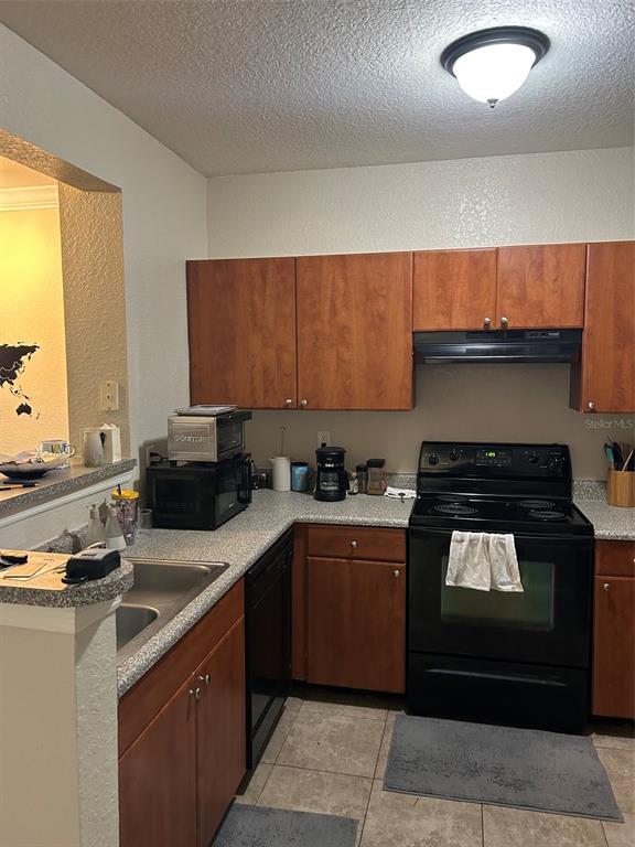 A kitchen features wood cabinets, black appliances, and a gray speckled countertop — 304 E SOUTH STREET UNIT 6025, ORLANDO, FL