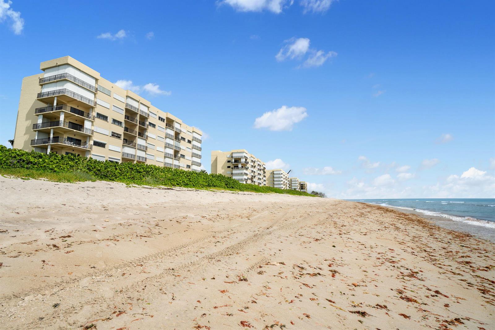 A sandy beach stretches along the coast in front of several multi-story apartment buildings — 7420 S Ocean Drive # 314, Jensen Beach FL 34957, JENSEN BEACH, FL