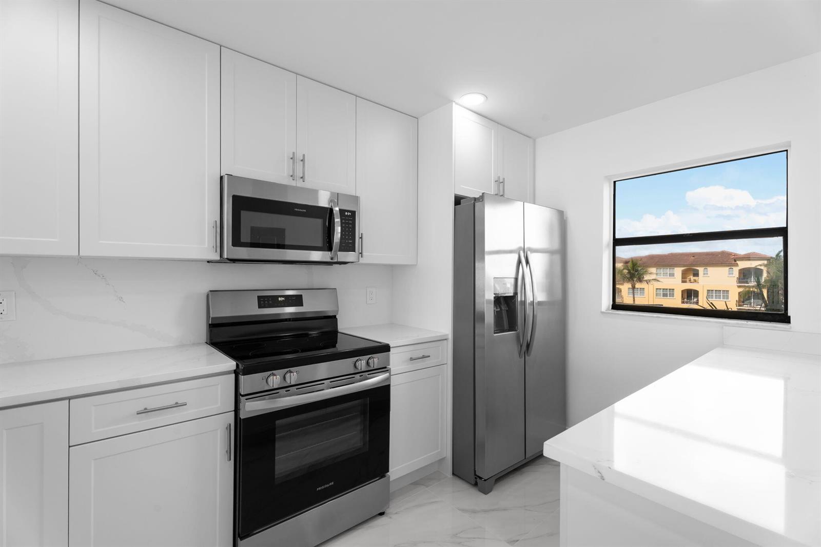 A modern kitchen features white cabinets, stainless steel appliances, and quartz countertops — 7420 S Ocean Drive # 314, Jensen Beach FL 34957, JENSEN BEACH, FL