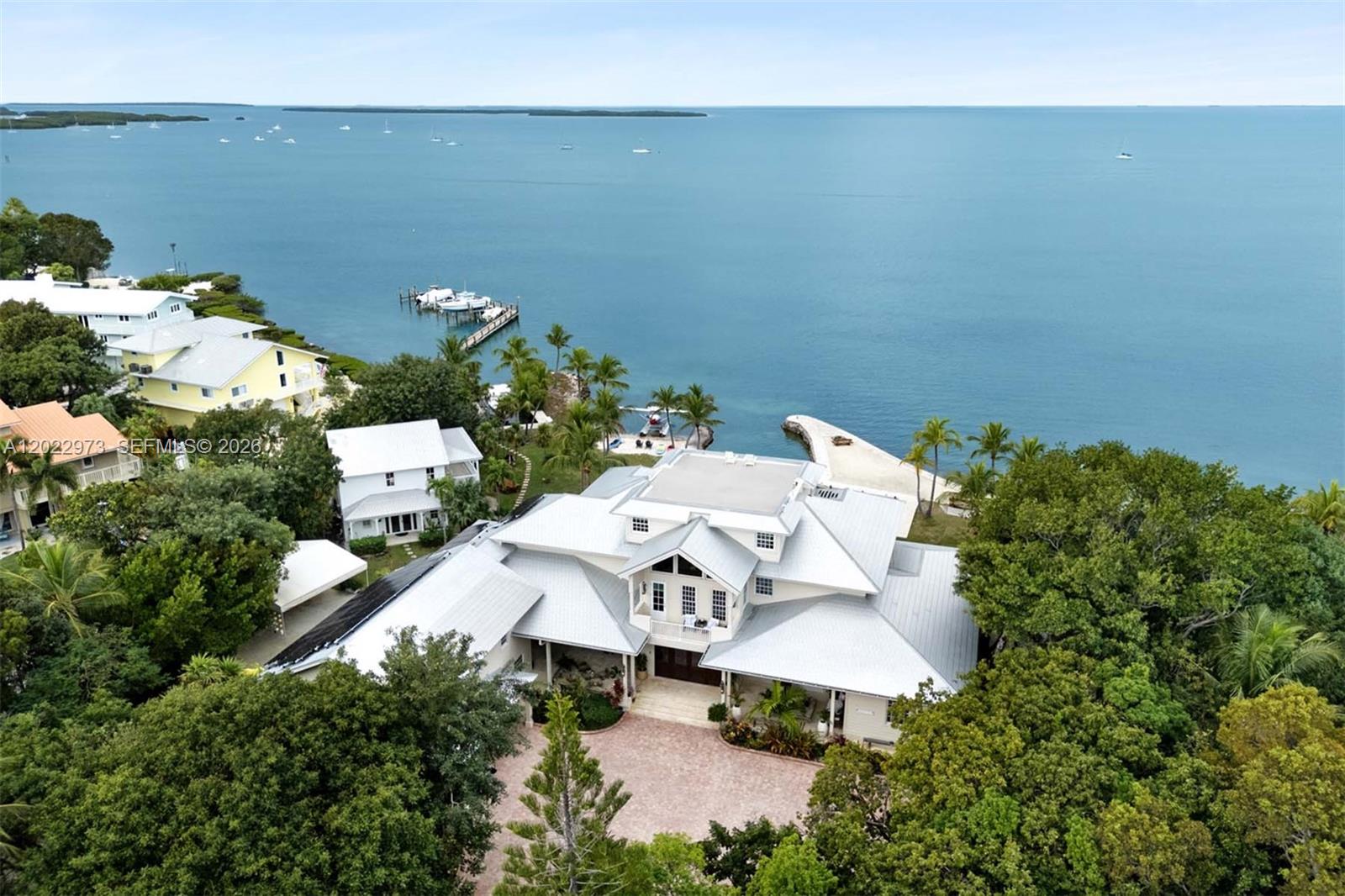 An aerial view shows a large waterfront house with a metal roof and brick driveway — 82768 Overseas Highway, Islamorada FL 33036, ISLAMORADA, FL