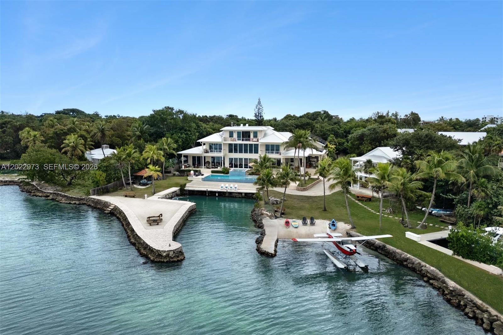 An aerial view shows a waterfront mansion with a pool, private dock, and seaplane — 82768 Overseas Highway, Islamorada FL 33036, ISLAMORADA, FL