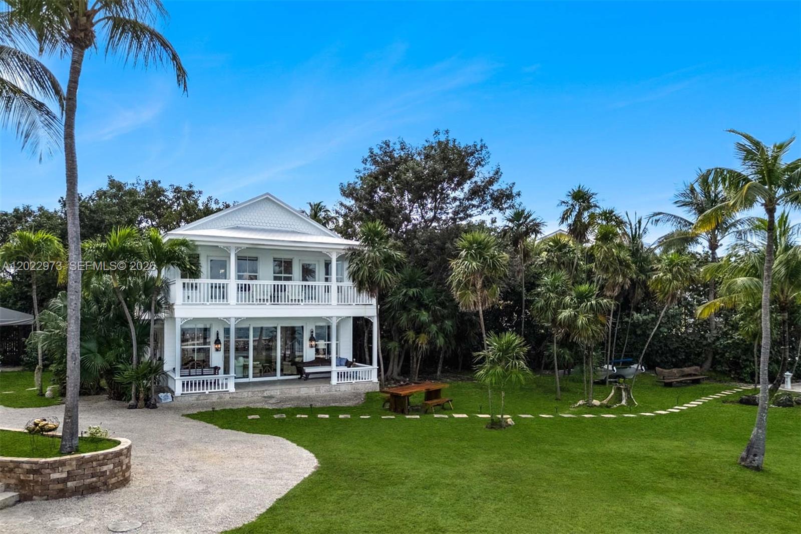A two-story white house with a wraparound porch sits on a grassy, palm-filled lot — 82768 Overseas Highway, Islamorada FL 33036, ISLAMORADA, FL
