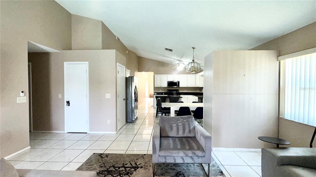 An open-concept living and dining area features white tile flooring, vaulted ceilings, and white cabinetry — 223 LAKE DAVENPORT ESTATES DRIVE, DAVENPORT, FL
