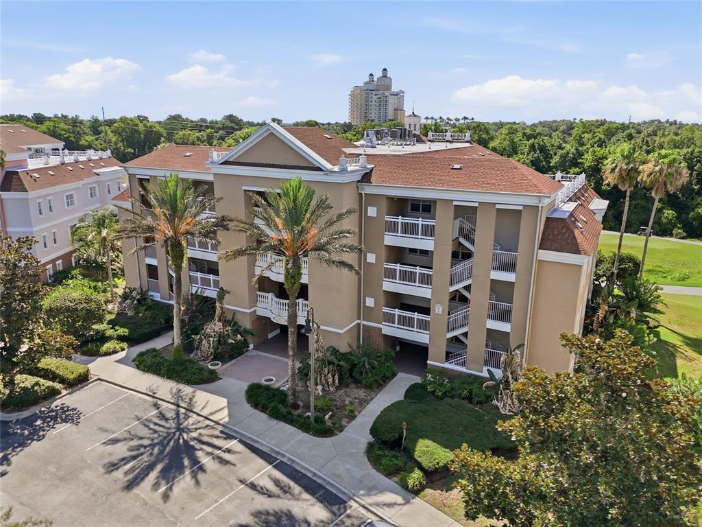 An aerial view of a multi-story tan apartment building with a brown roof and balconies — 7612 CABANA COURT UNIT 202, REUNION, FL