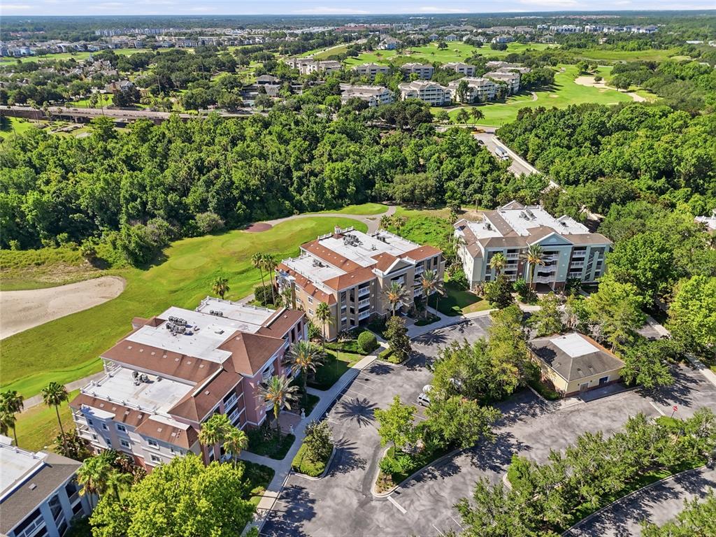 An aerial view shows three multi-story apartment buildings surrounded by a golf course and trees — 7612 CABANA COURT UNIT 202, REUNION, FL