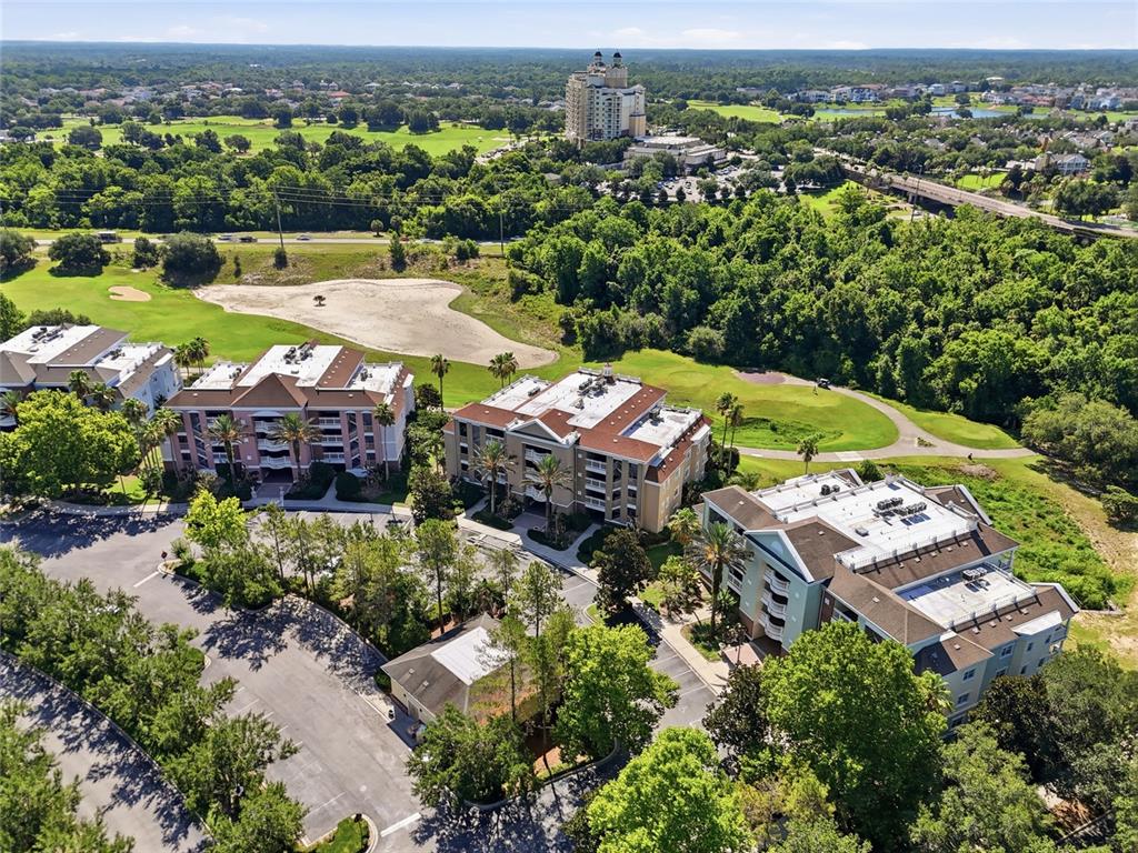 An aerial view shows three multi-story apartment buildings surrounded by trees and a golf course — 7612 CABANA COURT UNIT 202, REUNION, FL