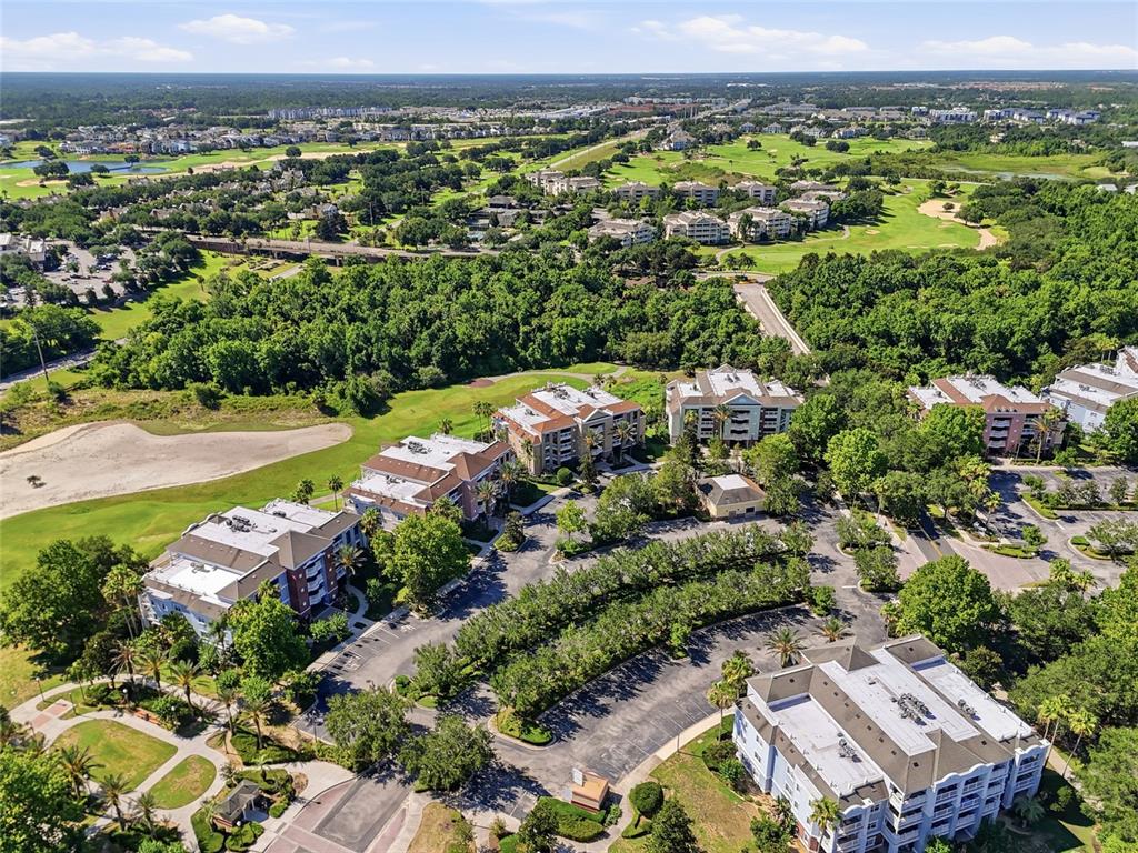 An aerial view shows several multi-story apartment buildings surrounded by trees, parking lots, and golf courses — 7612 CABANA COURT UNIT 202, REUNION, FL