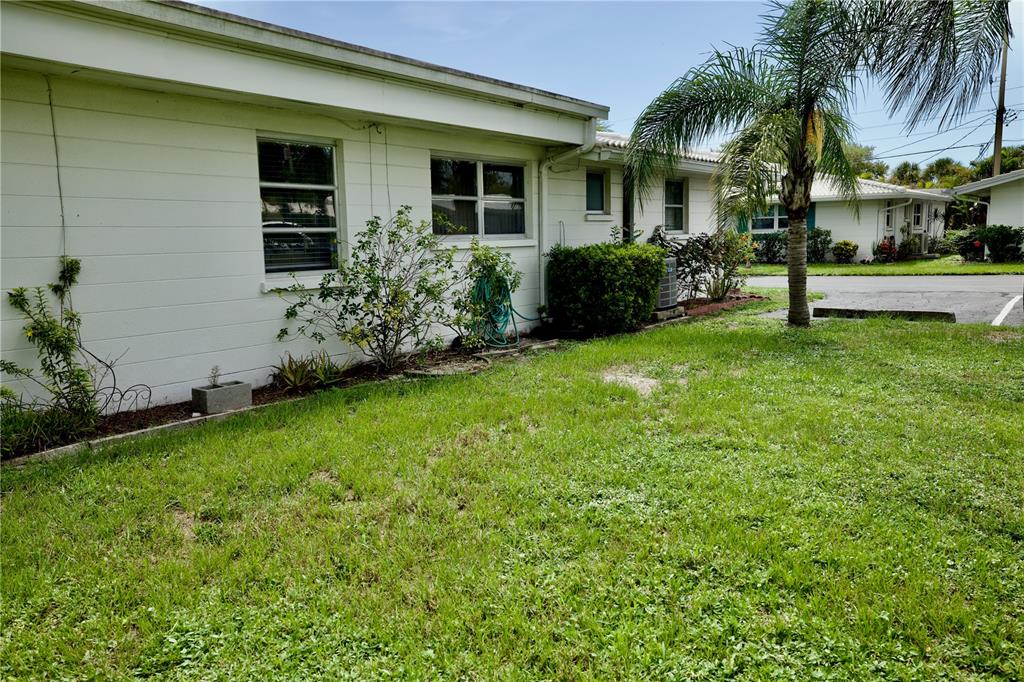A white single-story house exterior features a grassy yard, a palm tree, and several windows — 1741 CARIBBEAN CIRCLE UNIT 13, VENICE, FL