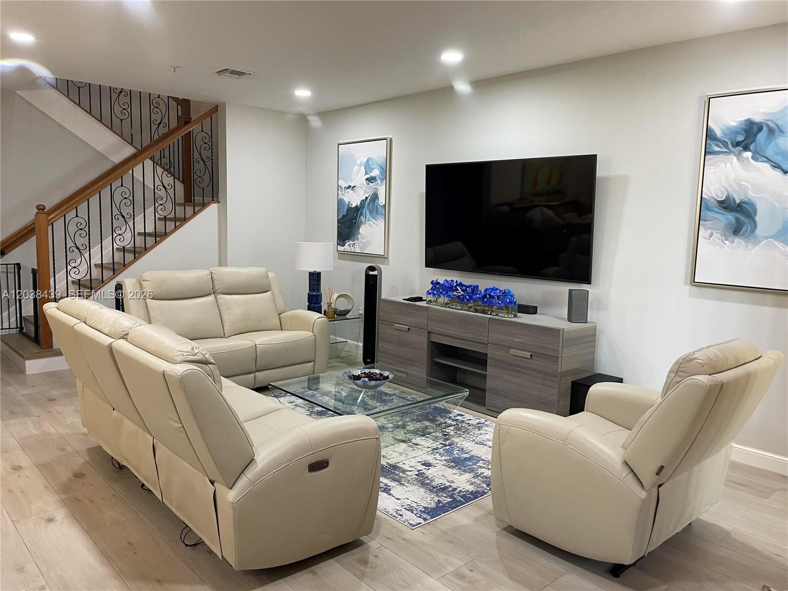 A living room features light-colored leather sofas, a glass coffee table, and a wall-mounted television — 2900 NW 125th Ave # 107, Sunrise FL 33323, SUNRISE, FL