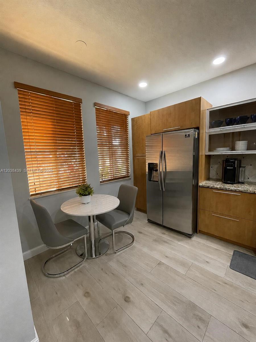 A kitchen features light wood cabinets, stainless steel appliances, and a small circular dining table — 2900 NW 125th Ave # 107, Sunrise FL 33323, SUNRISE, FL