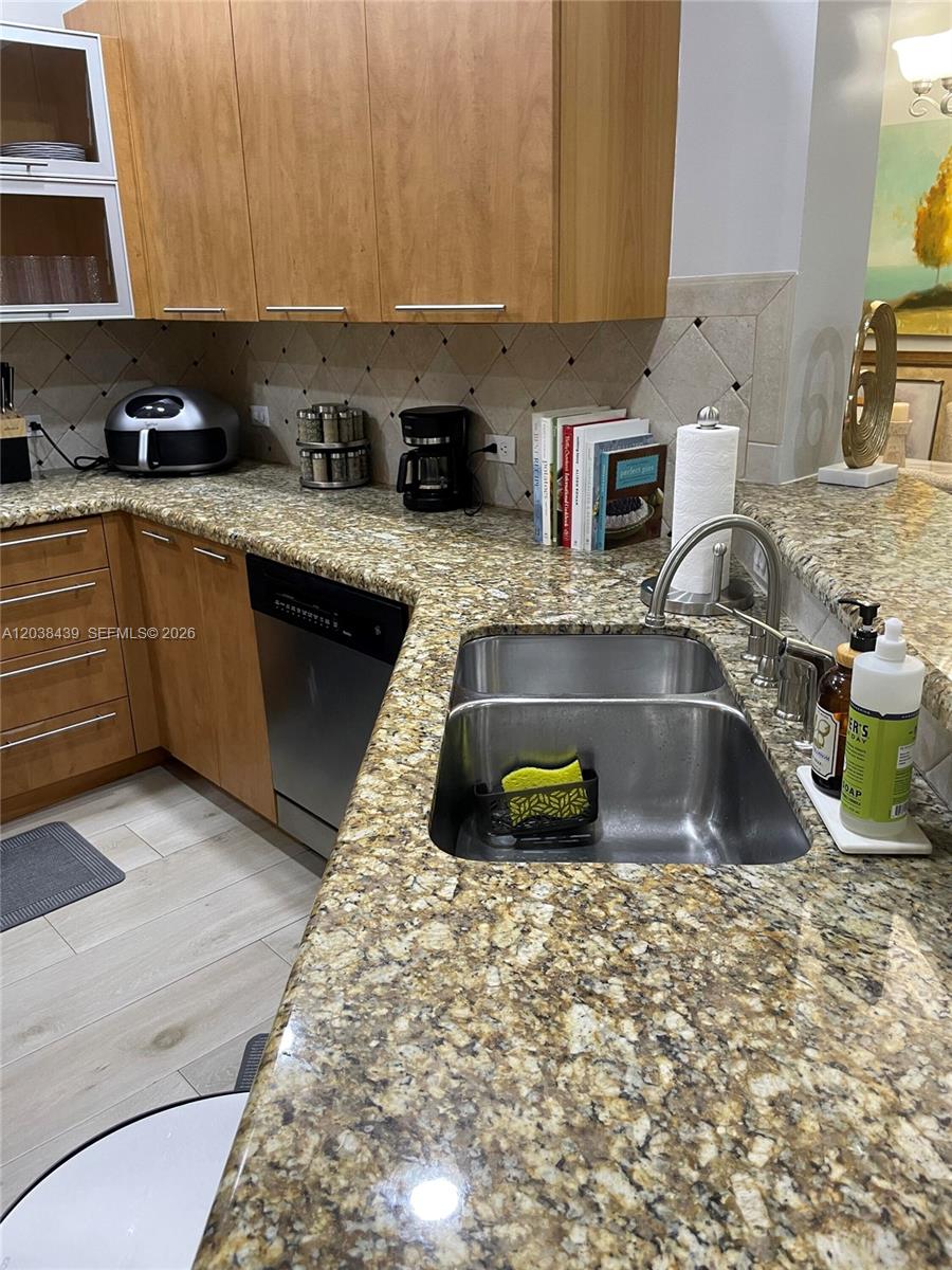 A kitchen features wood cabinets, granite countertops, a double-basin sink, and a dishwasher — 2900 NW 125th Ave # 107, Sunrise FL 33323, SUNRISE, FL