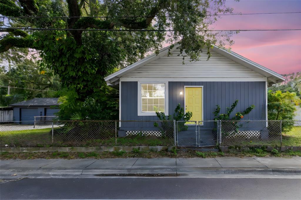 A blue house with a yellow front door sits behind a chain-link fence — 701 E 25TH STREET, SANFORD, FL