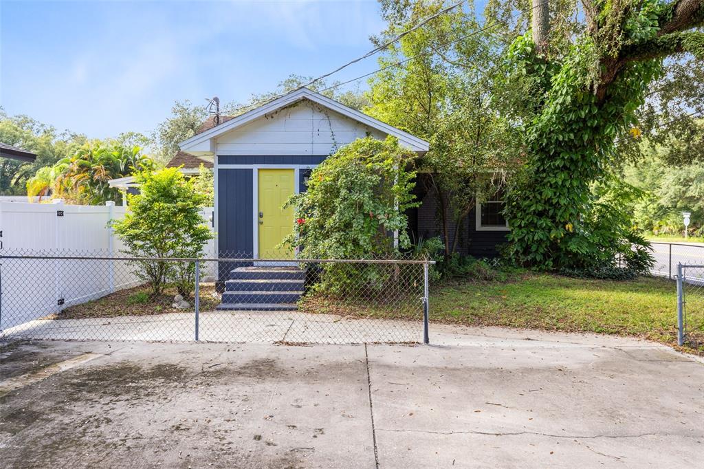 A small house with dark blue siding, a bright yellow door, and a chain-link fence — 701 E 25TH STREET, SANFORD, FL