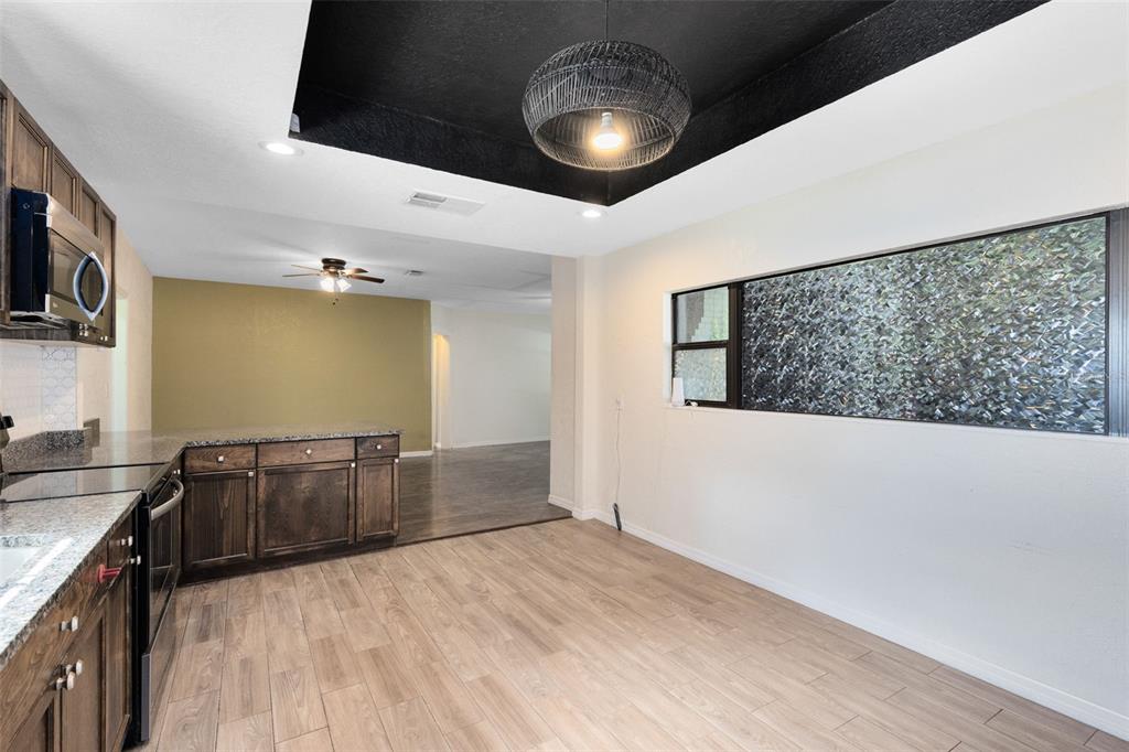 A kitchen with dark wood cabinets, granite countertops, and a black tray ceiling with lighting — 701 E 25TH STREET, SANFORD, FL