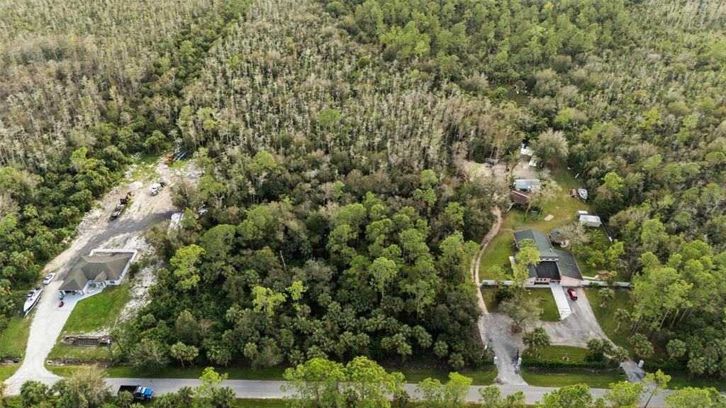 An aerial view shows two houses surrounded by dense forest and a paved road — 4870 30TH AVENUE SE, NAPLES, FL