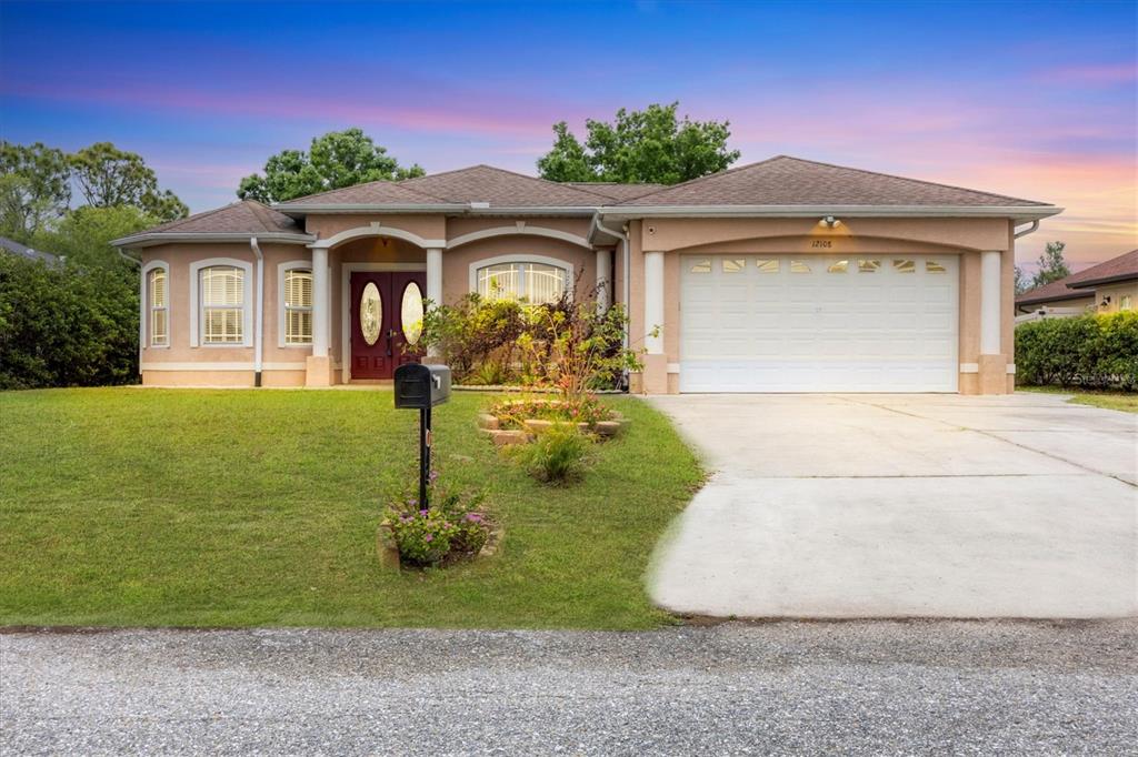 A single-story tan stucco house with a two-car garage and a front lawn — 12108 HERNANDO ROAD, NORTH PORT, FL