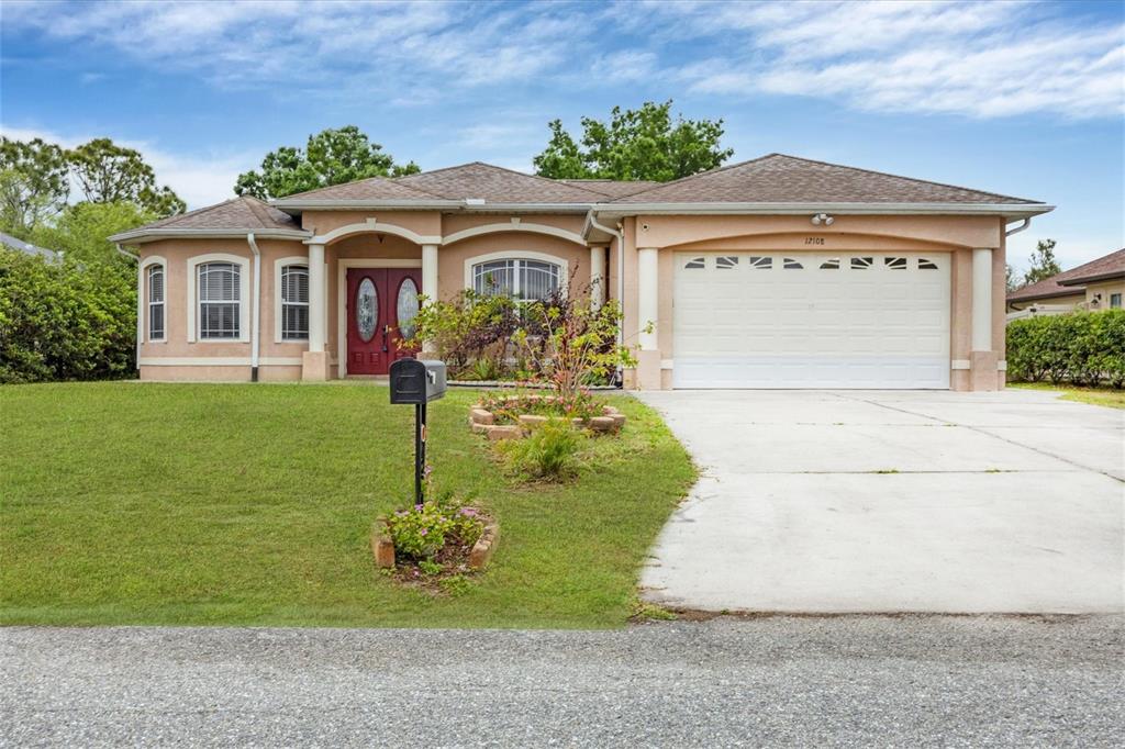 A single-story house with a beige stucco exterior, a two-car garage, and a front lawn — 12108 HERNANDO ROAD, NORTH PORT, FL