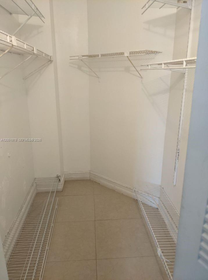 A walk-in closet features white wire shelving and light-colored tile flooring — 7125 NW 186th St # B209, Hialeah FL 33015, HIALEAH, FL