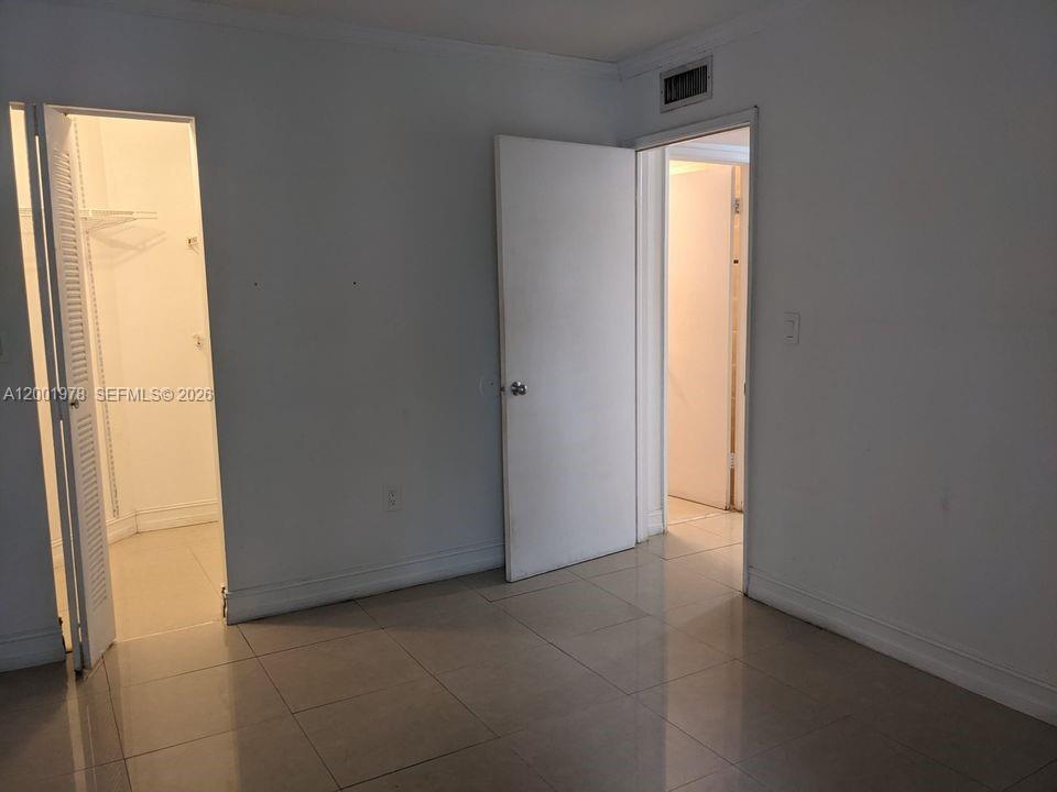 A room with light-colored tile flooring features two open doorways leading to a closet and bathroom — 7125 NW 186th St # B209, Hialeah FL 33015, HIALEAH, FL