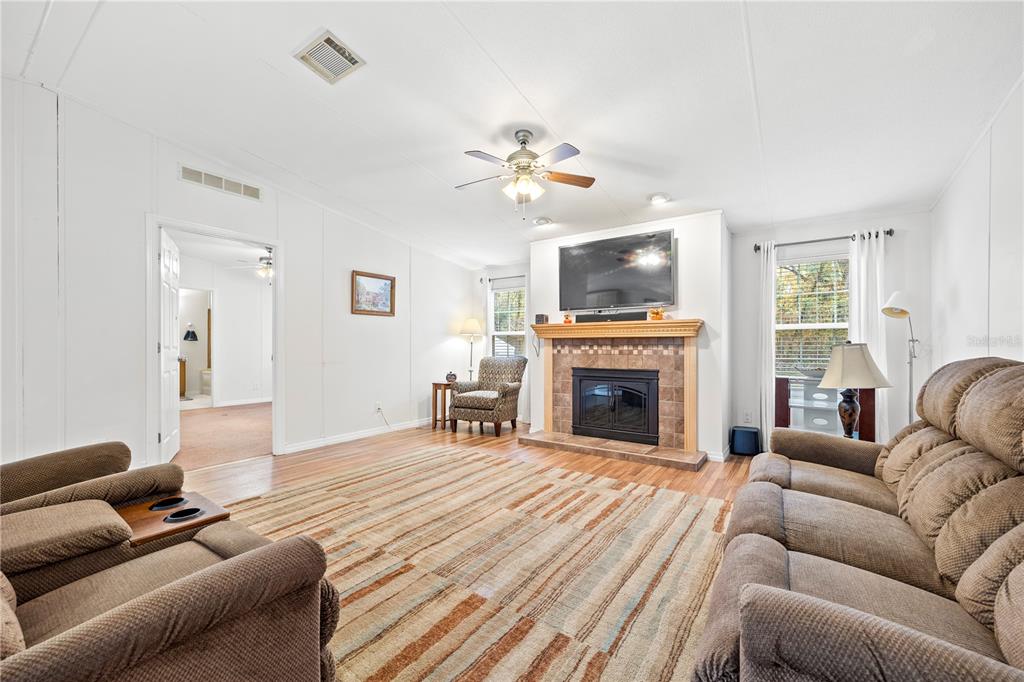 A living room features a fireplace with a mounted television, wood flooring, and brown furniture — 1366 SW CENTRAL TERRACE, FORT WHITE, FL