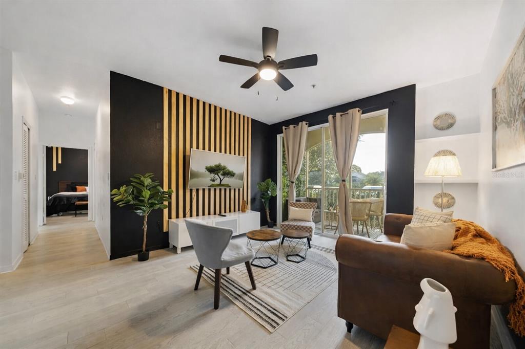 A living room features a wood-slat accent wall, a brown sofa, and a sliding glass door — 8824 DUNES COURT COURT UNIT 103, KISSIMMEE, FL