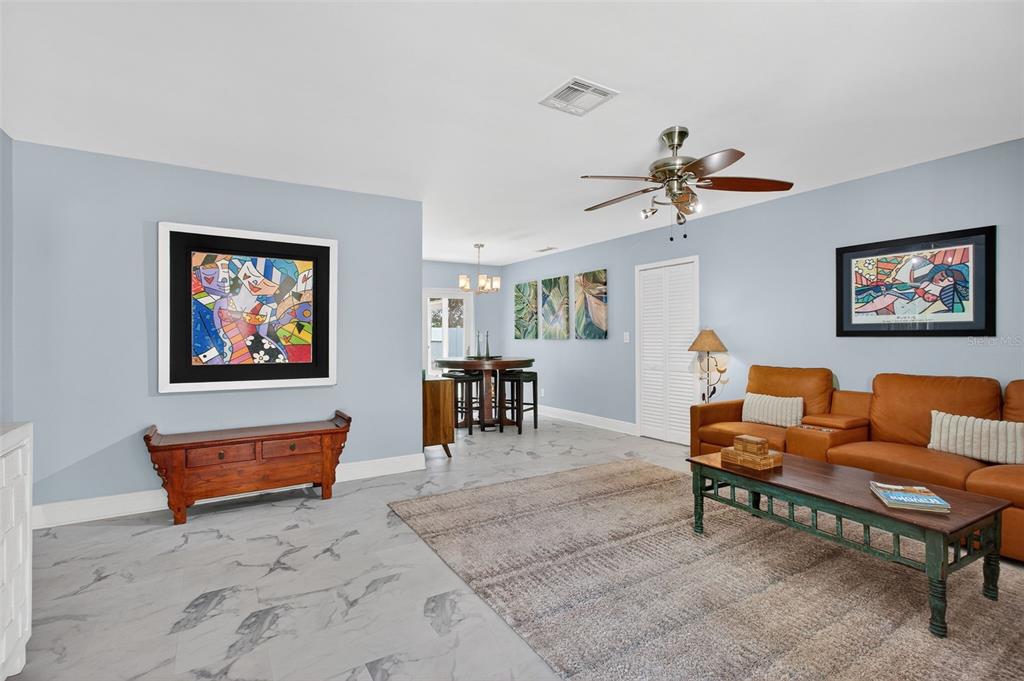 A living room with light blue walls, marble-look tile flooring, and a brown leather sofa — 5723 1ST STREET NE, ST PETERSBURG, FL