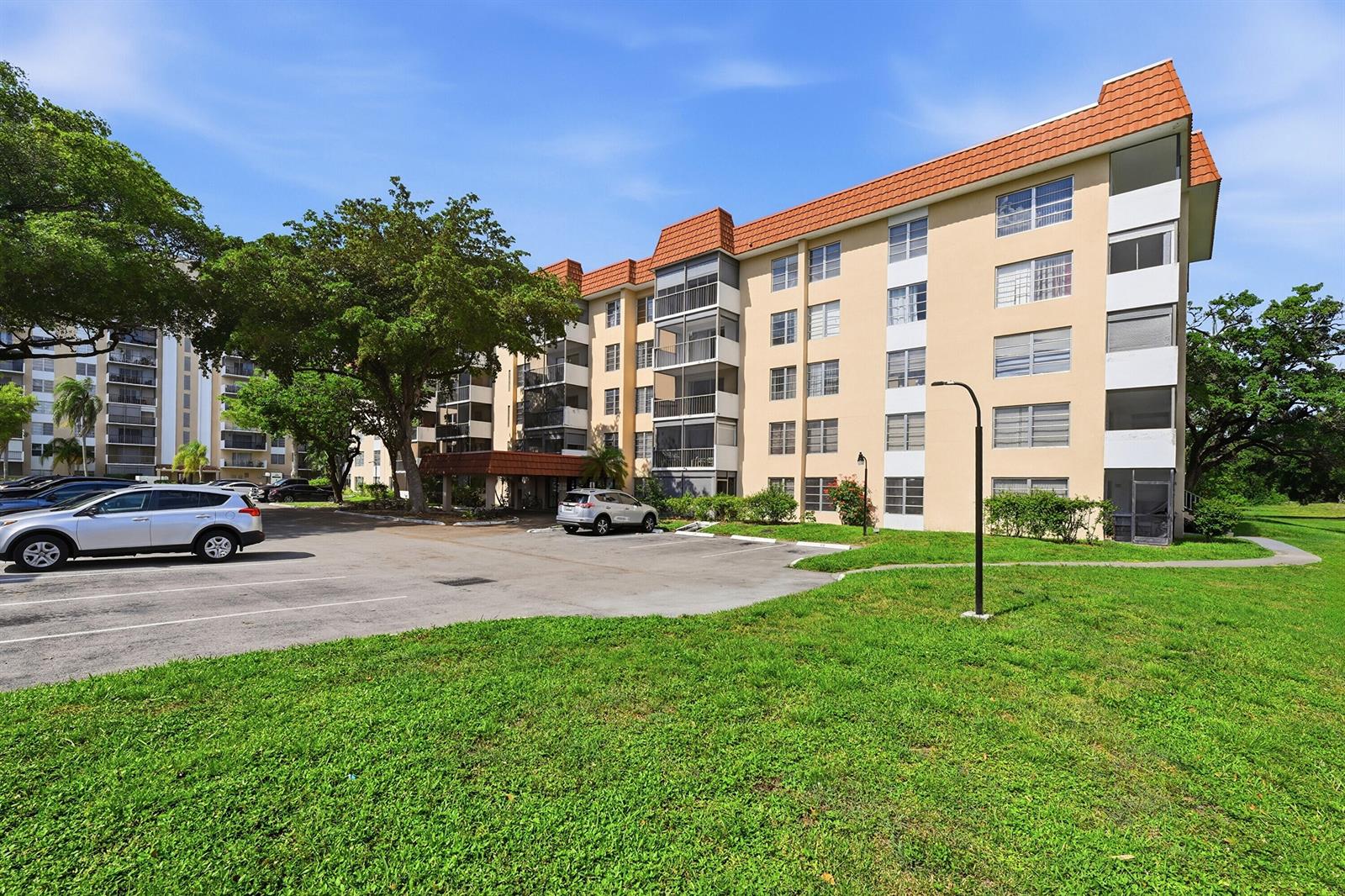 A multi-story apartment building with a parking lot and green lawn in the foreground — 4158 Inverrary Drive # 511, Lauderhill FL 33319, LAUDERHILL, FL