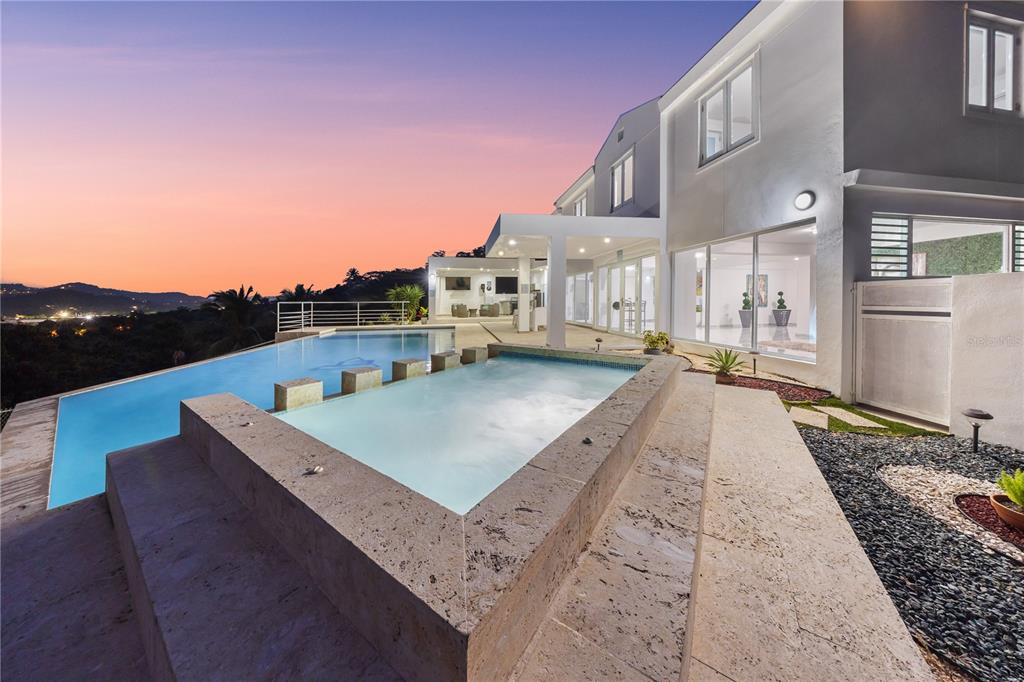 A modern house exterior features a tiered swimming pool and spa overlooking a sunset landscape — Bo. San Antonio Km 2.0 CARR. 739, CAGUAS, PR