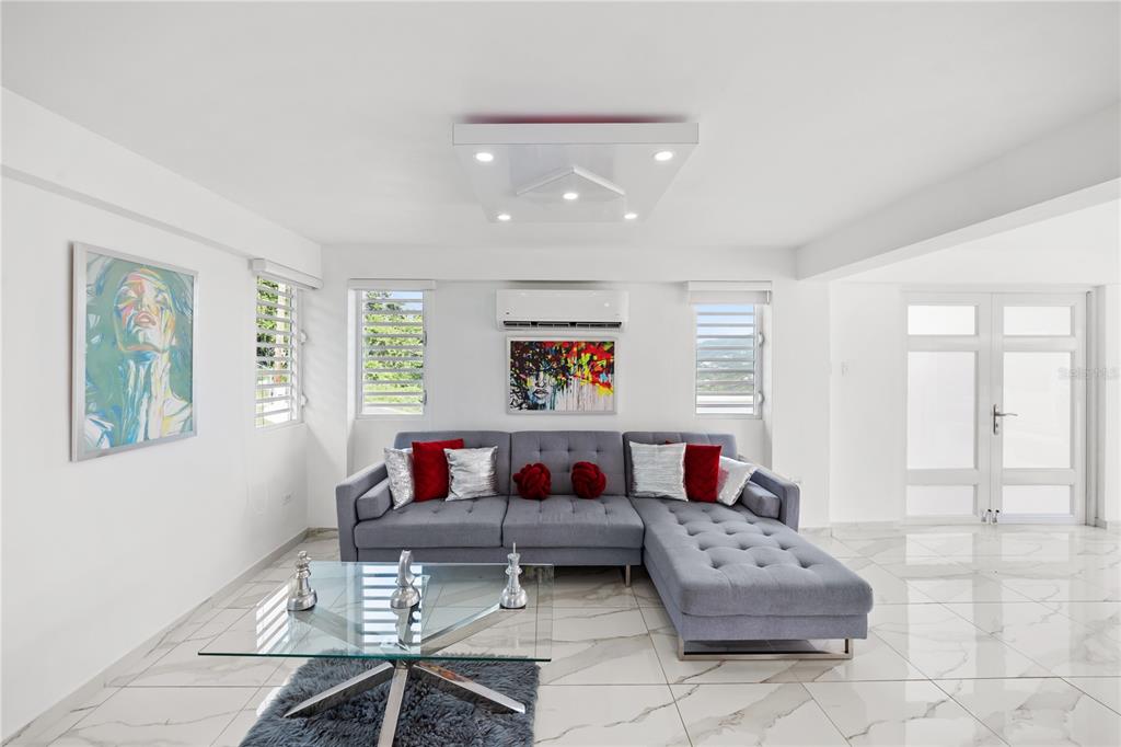 A living room features a grey sectional sofa, glass coffee table, and white marble flooring — Bo. San Antonio Km 2.0 CARR. 739, CAGUAS, PR
