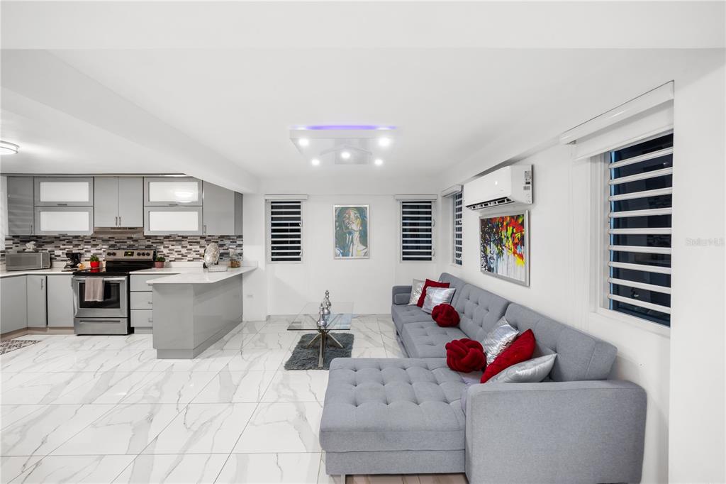 A modern open-concept living room and kitchen with gray cabinetry, white marble floors, and sofa — Bo. San Antonio Km 2.0 CARR. 739, CAGUAS, PR