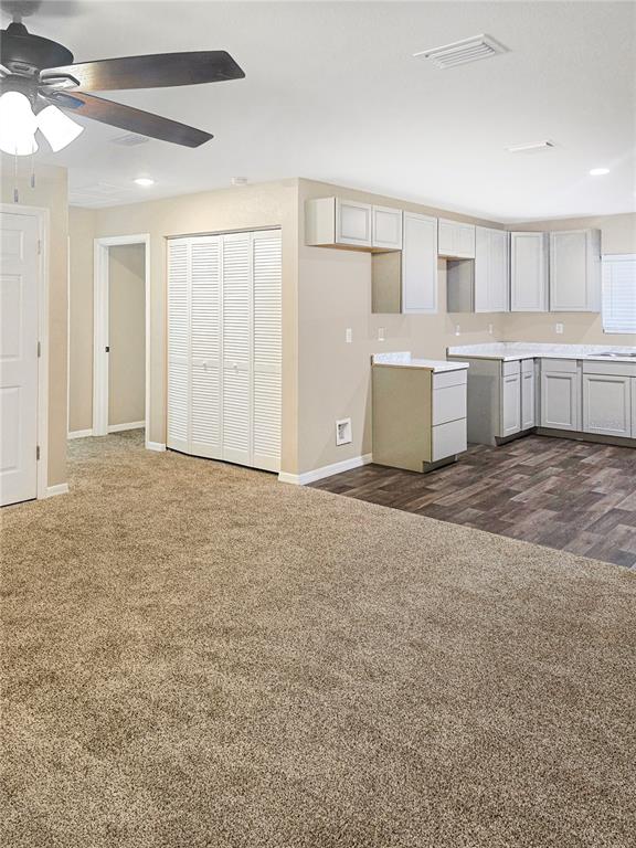 An open-concept room features a carpeted living area, a kitchen with gray cabinets, and flooring — 19920 SW 108TH PLACE, DUNNELLON, FL