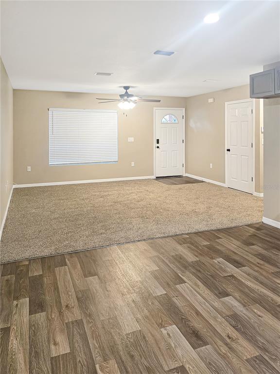 A living room features beige carpet, light tan walls, a ceiling fan, and wood-look flooring — 19920 SW 108TH PLACE, DUNNELLON, FL