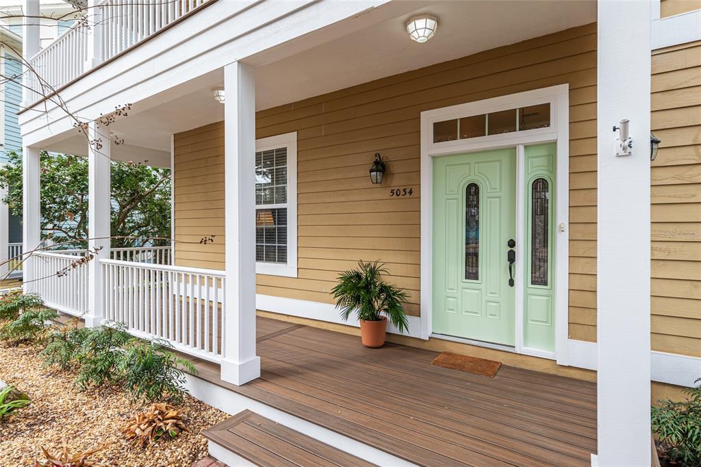 A light green front door with sidelights sits on a covered porch with wooden decking — 5034 NW 11TH PLACE, GAINESVILLE, FL
