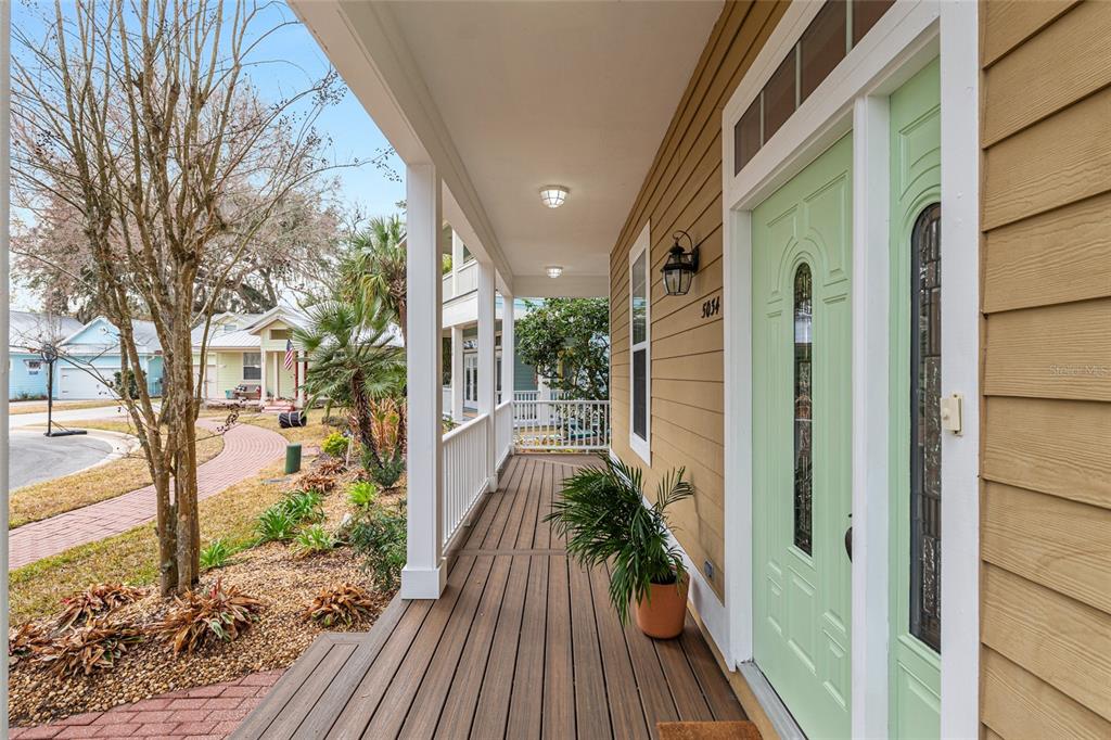 A covered wooden porch with a light green front door and tan siding — 5034 NW 11TH PLACE, GAINESVILLE, FL