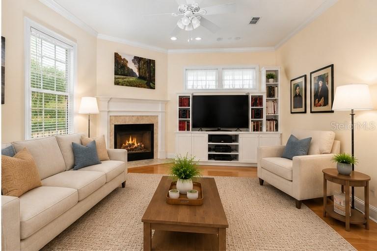 A living room features a fireplace, a television on a media console, and neutral furniture — 5034 NW 11TH PLACE, GAINESVILLE, FL